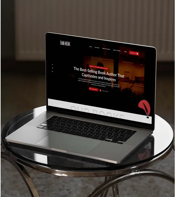 A laptop on a table displaying a red and black website design.