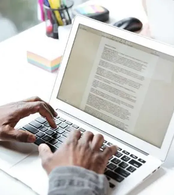A person focused on typing on a laptop computer, with hands positioned over the keyboard.